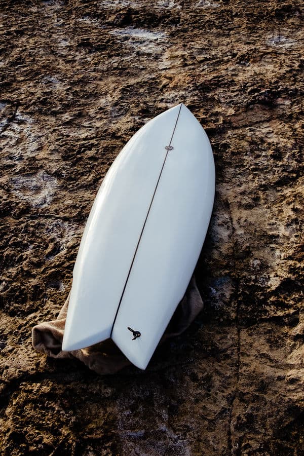 Hand shaping the rails of a custom surfboard
