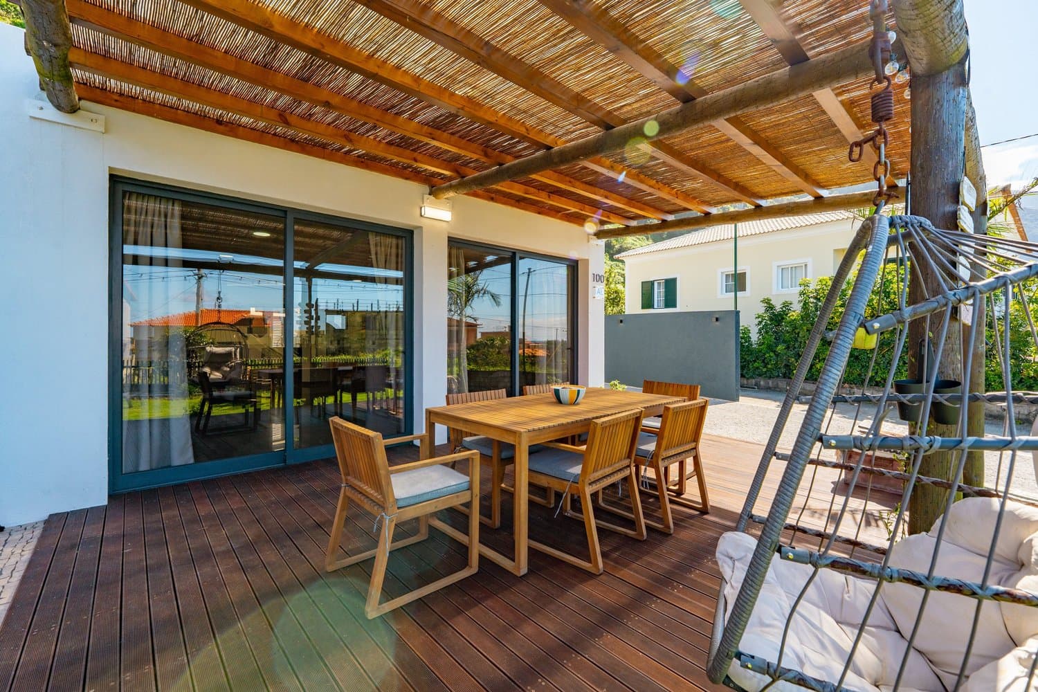 Covered outdoor dining deck with a swing chair at House Ash, Fajã Lodges